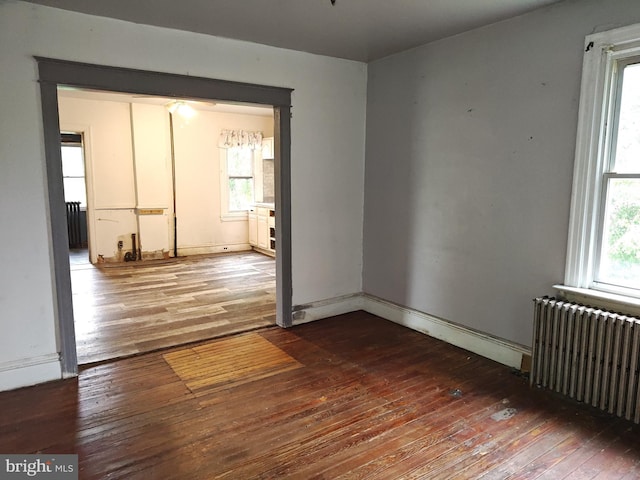 unfurnished room with radiator heating unit, hardwood / wood-style floors, and healthy amount of natural light