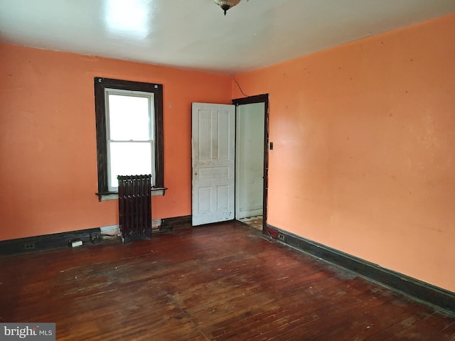 unfurnished room with radiator, hardwood / wood-style floors, and baseboards