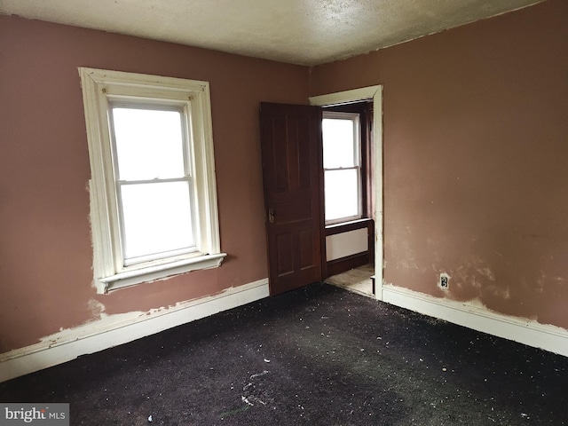 carpeted spare room with plenty of natural light and baseboards