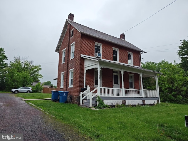 view of front facade with a porch, a chimney, and brick siding