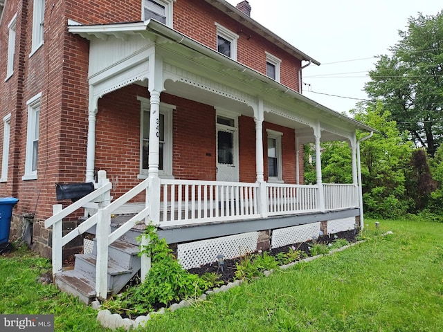 view of front of property featuring covered porch, brick siding, and a front yard