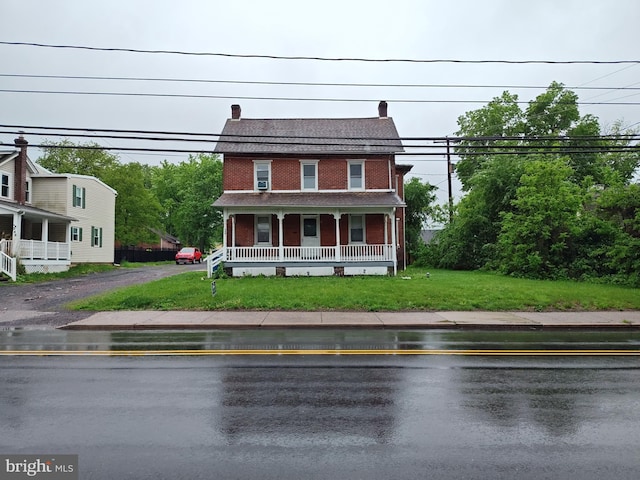 view of front of house with a porch, brick siding, and a front yard