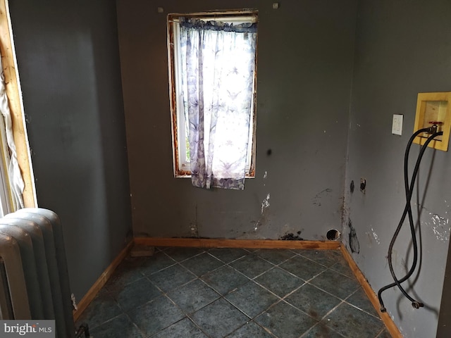 unfurnished room with radiator, baseboards, and dark tile patterned floors
