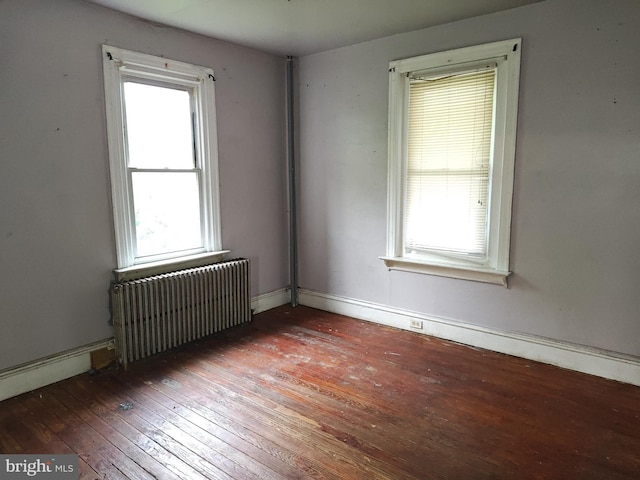 spare room with radiator heating unit, wood-type flooring, and plenty of natural light
