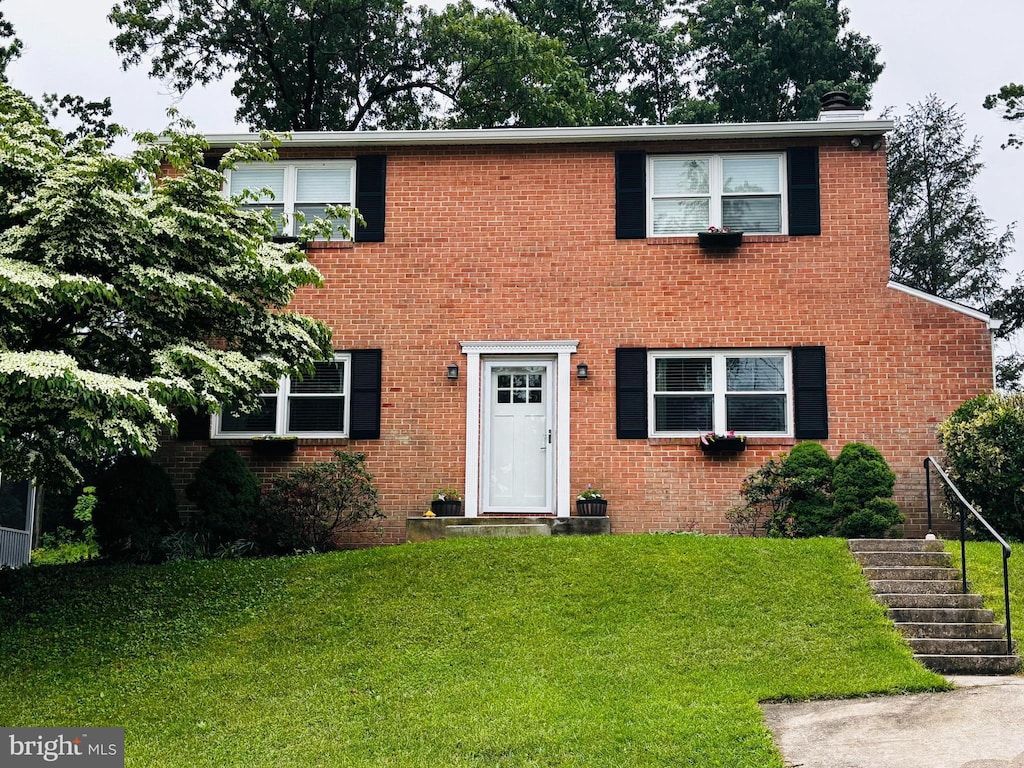 colonial home with a front yard, stairs, and brick siding