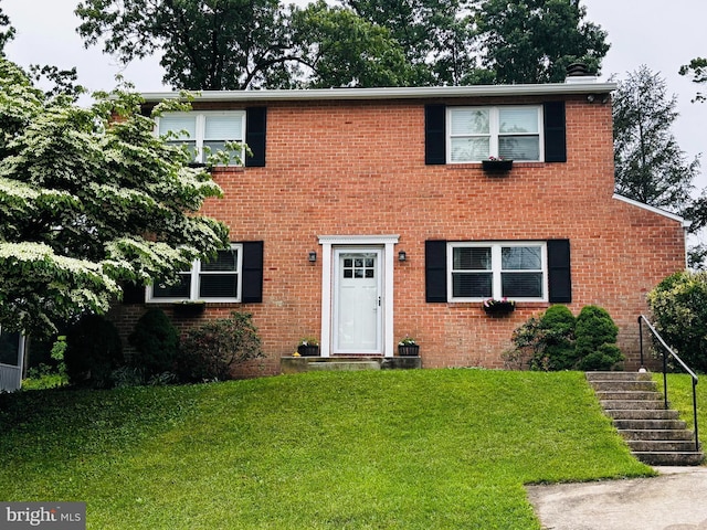 colonial home with a front yard, stairs, and brick siding