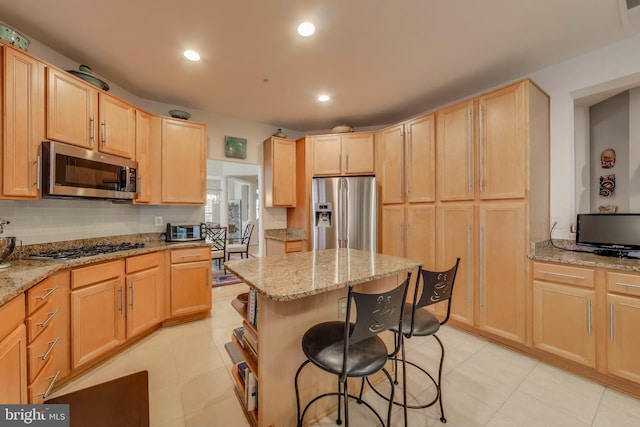 13605 Autumn End Ter, Laurel, MD 20707 - kitchen featuring appliances with stainless steel finishes, light brown cabinetry, a breakfast bar area, light stone counters, and recessed lighting