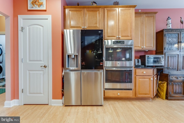 15149 Coultlands Reach, Milton, DE 19968 - kitchen with appliances with stainless steel finishes, estacked washer and dryer, light wood-style floors, and dark stone countertops