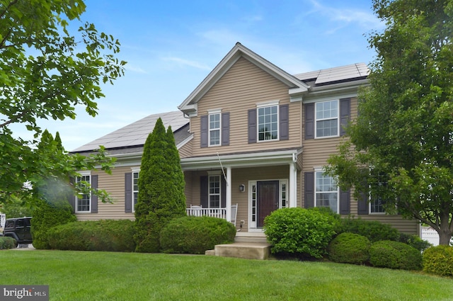 view of front of property with covered porch, solar panels, and a front lawn