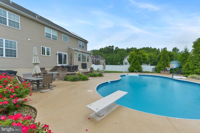 view of pool with a diving board, a patio, and fence