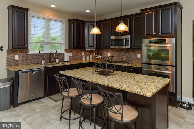 kitchen featuring a sink, appliances with stainless steel finishes, backsplash, a center island, and light stone counters