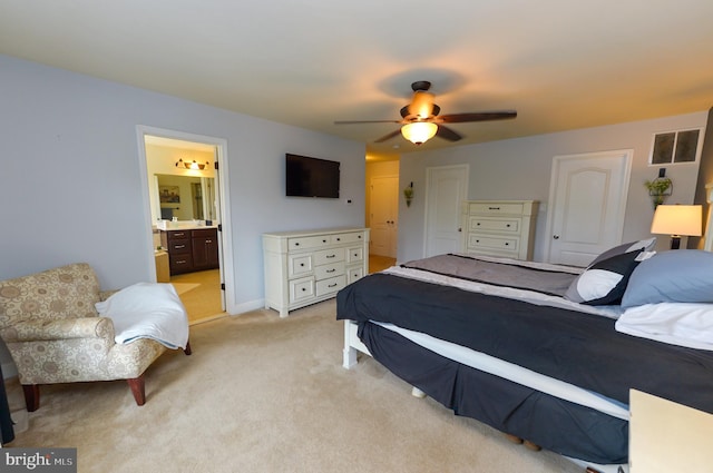 bedroom with light colored carpet, a ceiling fan, and ensuite bathroom