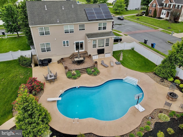 view of swimming pool with a diving board, a patio area, outdoor dining area, and an outdoor living space with a fire pit