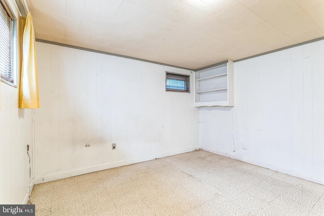 basement with tile patterned floors, baseboards, and wood walls