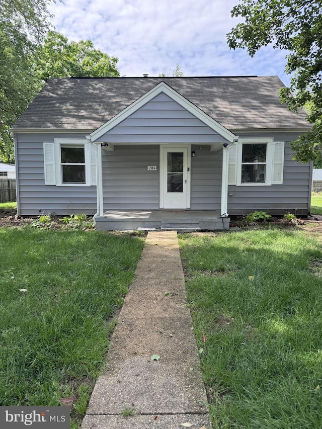 bungalow-style home featuring a shingled roof, a front yard, and covered porch