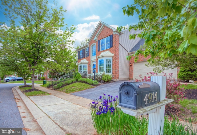 traditional-style home featuring brick siding, a garage, and driveway