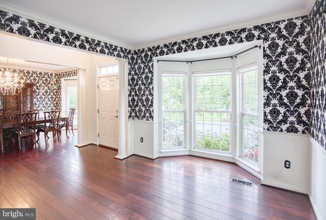 dining room with wallpapered walls, a chandelier, dark wood finished floors, ornamental molding, and plenty of natural light