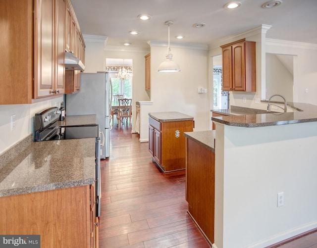 kitchen with electric stove, crown molding, a peninsula, under cabinet range hood, and brown cabinetry