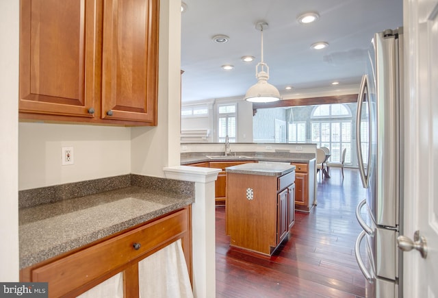 kitchen featuring freestanding refrigerator, a sink, a peninsula, brown cabinetry, and recessed lighting