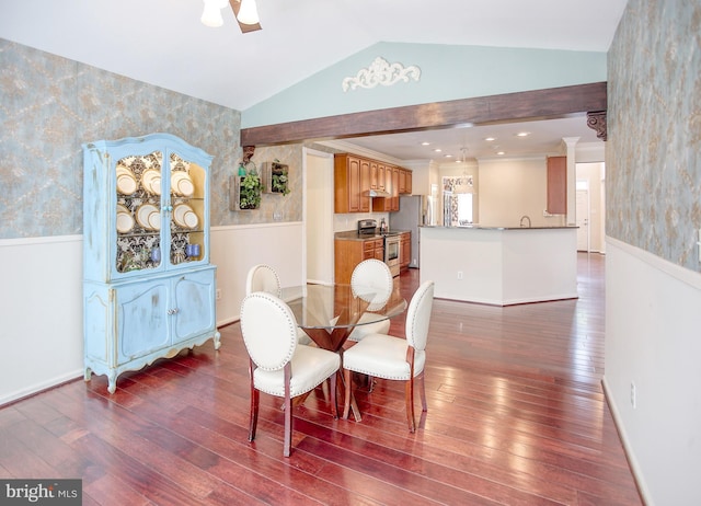 dining room featuring wallpapered walls, vaulted ceiling, dark wood-type flooring, wainscoting, and baseboards