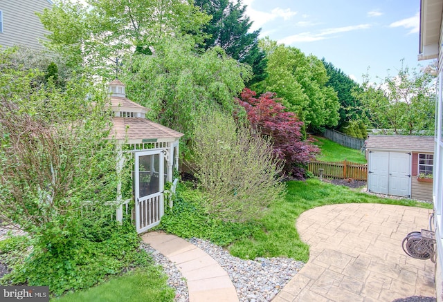 view of yard featuring a patio area, fence, a shed, and an outdoor structure