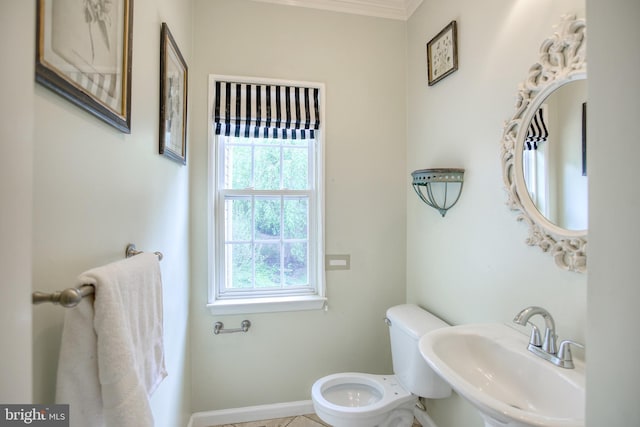 half bath featuring a sink, toilet, baseboards, and ornamental molding