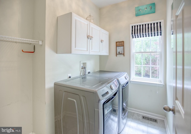 washroom with cabinet space, independent washer and dryer, baseboards, and light tile patterned floors