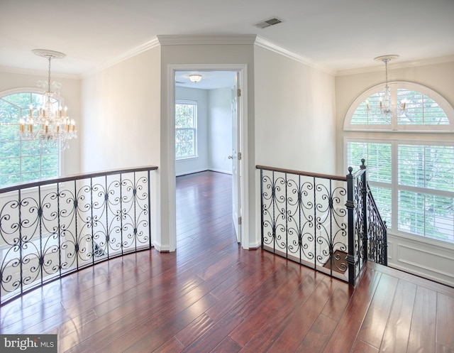 corridor with a chandelier, wood finished floors, an upstairs landing, and ornamental molding