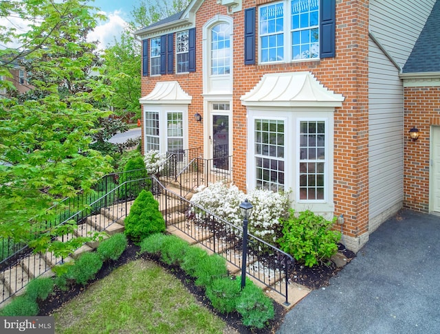 view of front facade with brick siding and stairs