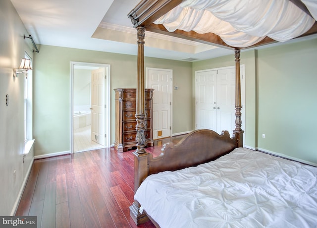 bedroom featuring baseboards, wood-type flooring, connected bathroom, and a closet