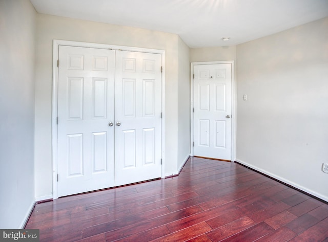 unfurnished bedroom featuring a closet, baseboards, and wood finished floors