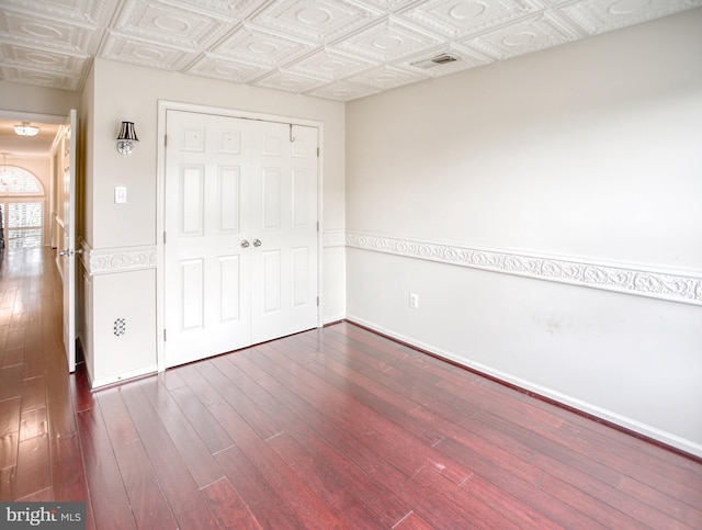 unfurnished bedroom featuring wood finished floors, an ornate ceiling, a closet, and baseboards