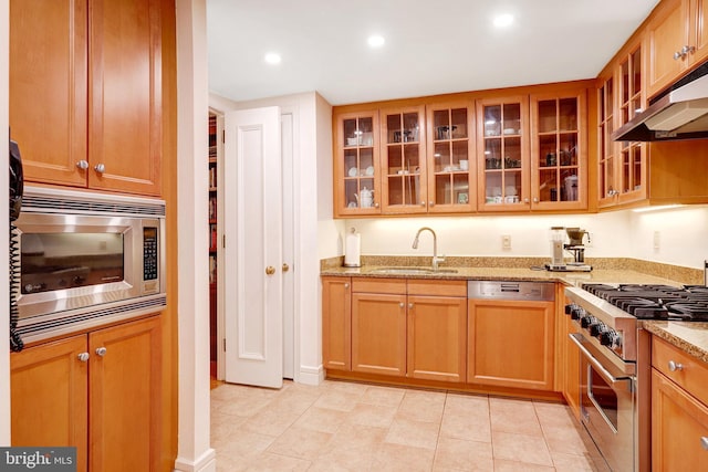 1155 23rd St NW Unit 2E, Washington, DC 20037 - kitchen featuring stainless steel appliances, a sink, under cabinet range hood, light stone countertops, and glass insert cabinets