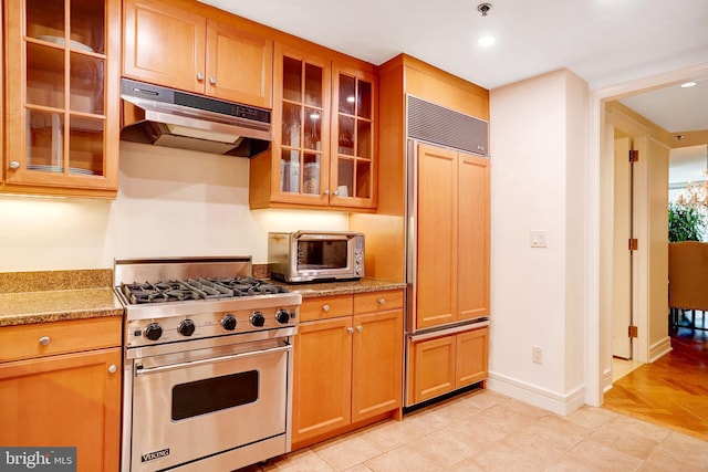 1155 23rd St NW Unit 2E, Washington, DC 20037 - kitchen with high quality appliances, under cabinet range hood, glass insert cabinets, baseboards, and light stone counters
