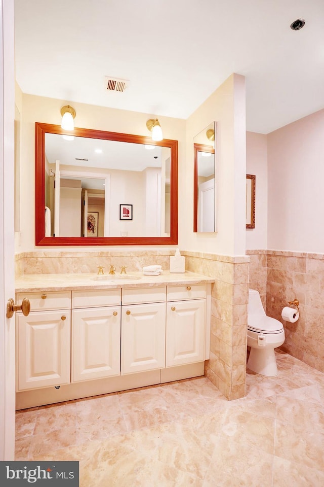 1155 23rd St NW Unit 2E, Washington, DC 20037 - bathroom with tile walls, vanity, wainscoting, tile patterned flooring, and toilet