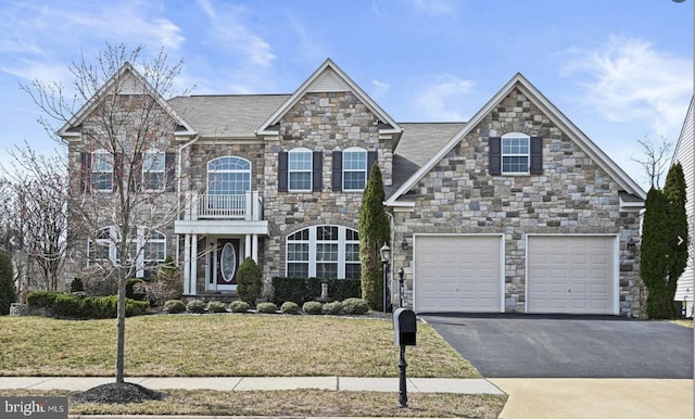 view of front of house with stone siding, driveway, a front lawn, and a balcony