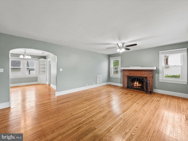 304 N Main St, Hebron, MD 21830 - unfurnished living room with arched walkways, light wood-type flooring, a ceiling fan, a fireplace, and a chandelier