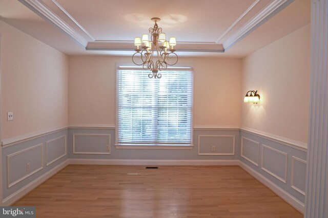 11504 Woodview Ct, Hagerstown, MD 21742 - spare room with a chandelier, a tray ceiling, crown molding, light wood-type flooring, and wainscoting