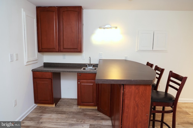11504 Woodview Ct, Hagerstown, MD 21742 - kitchen with a sink, dark countertops, light wood-style floors, a kitchen breakfast bar, and baseboards
