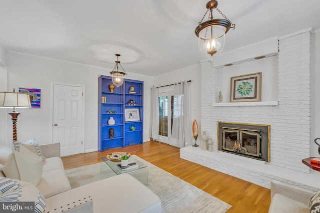 living room featuring wood finished floors, a brick fireplace, and ornamental molding