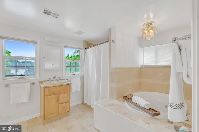 bathroom with a garden tub, vanity, baseboards, and a chandelier
