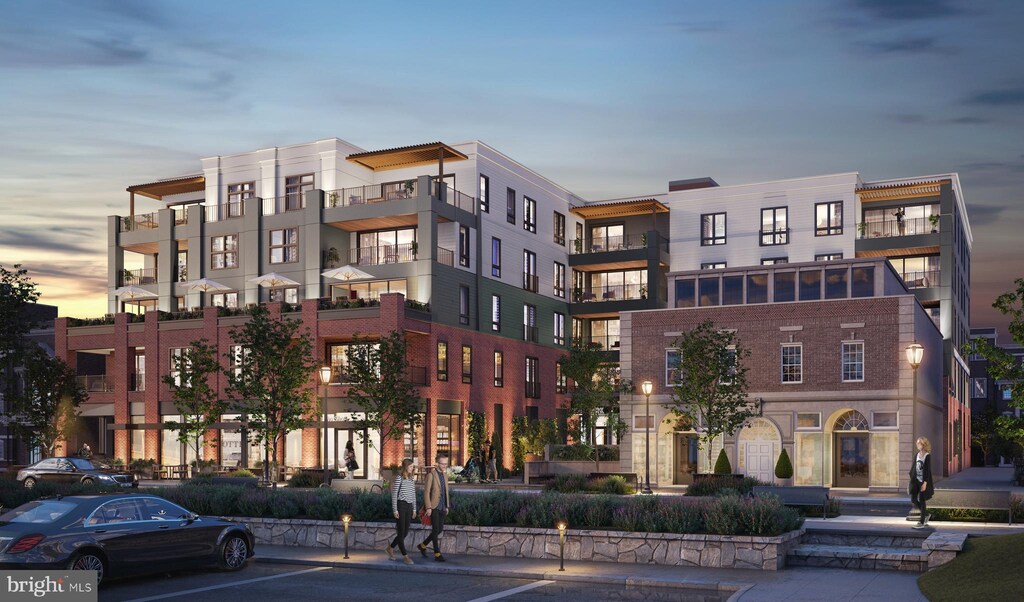 property at dusk with a view of apartment building / complex and uncovered parking