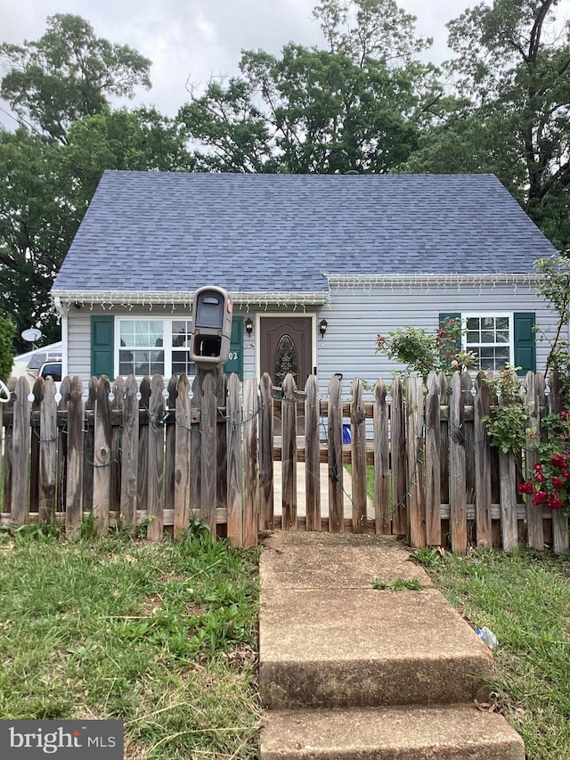 view of front facade featuring a shingled roof and fence
