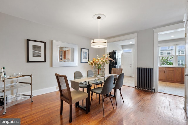 dining room with radiator heating unit, light wood-style floors, and baseboards