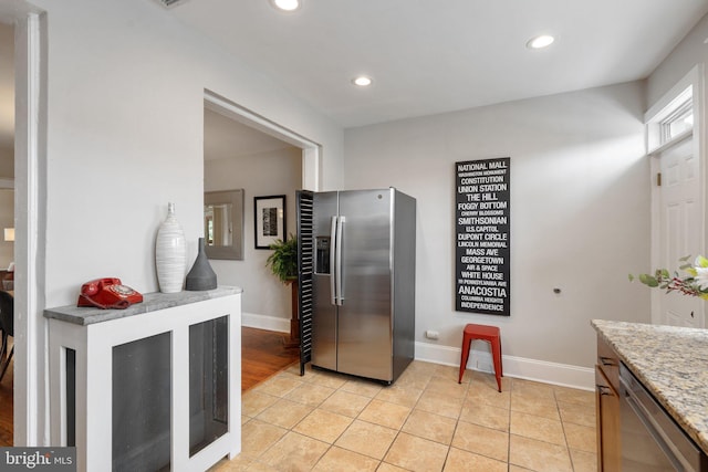 kitchen with appliances with stainless steel finishes, baseboards, recessed lighting, light stone countertops, and light tile patterned floors