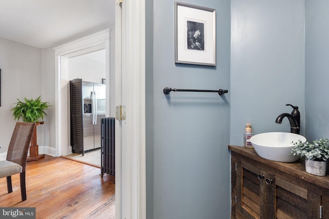 bathroom featuring wood finished floors, radiator heating unit, and vanity