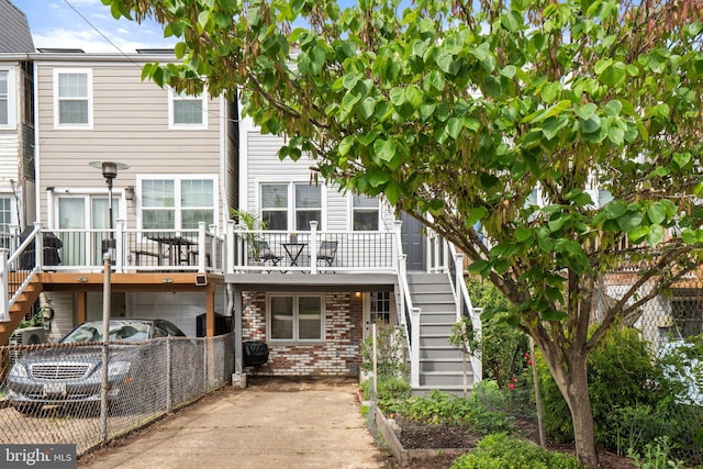 back of house with stairway, an attached garage, brick siding, and driveway