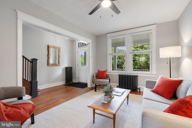 living room featuring radiator heating unit, wood finished floors, baseboards, and ceiling fan
