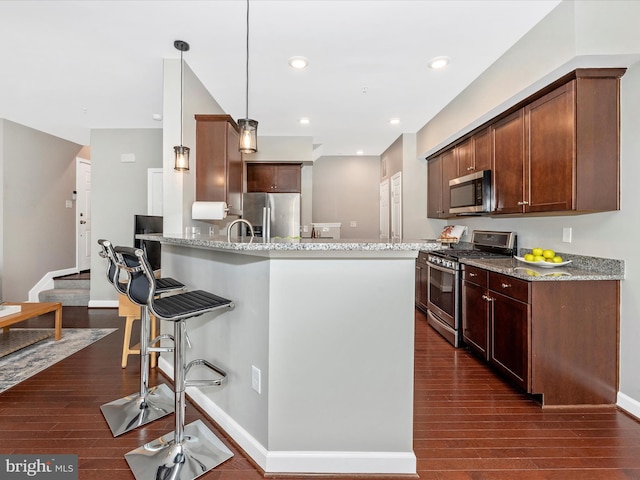 5920 Forum Sq ., Unit Frederick, MD 21703 - kitchen with stainless steel appliances, dark wood-type flooring, light stone countertops, a breakfast bar, and a peninsula