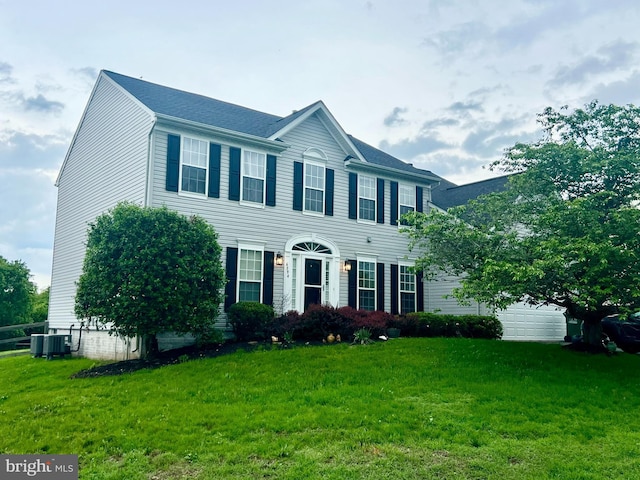 colonial-style house featuring a front lawn, a garage, and central AC